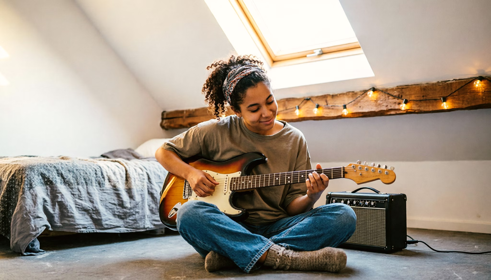 A teenage girl plays guitar in the newly converted attic room of her home