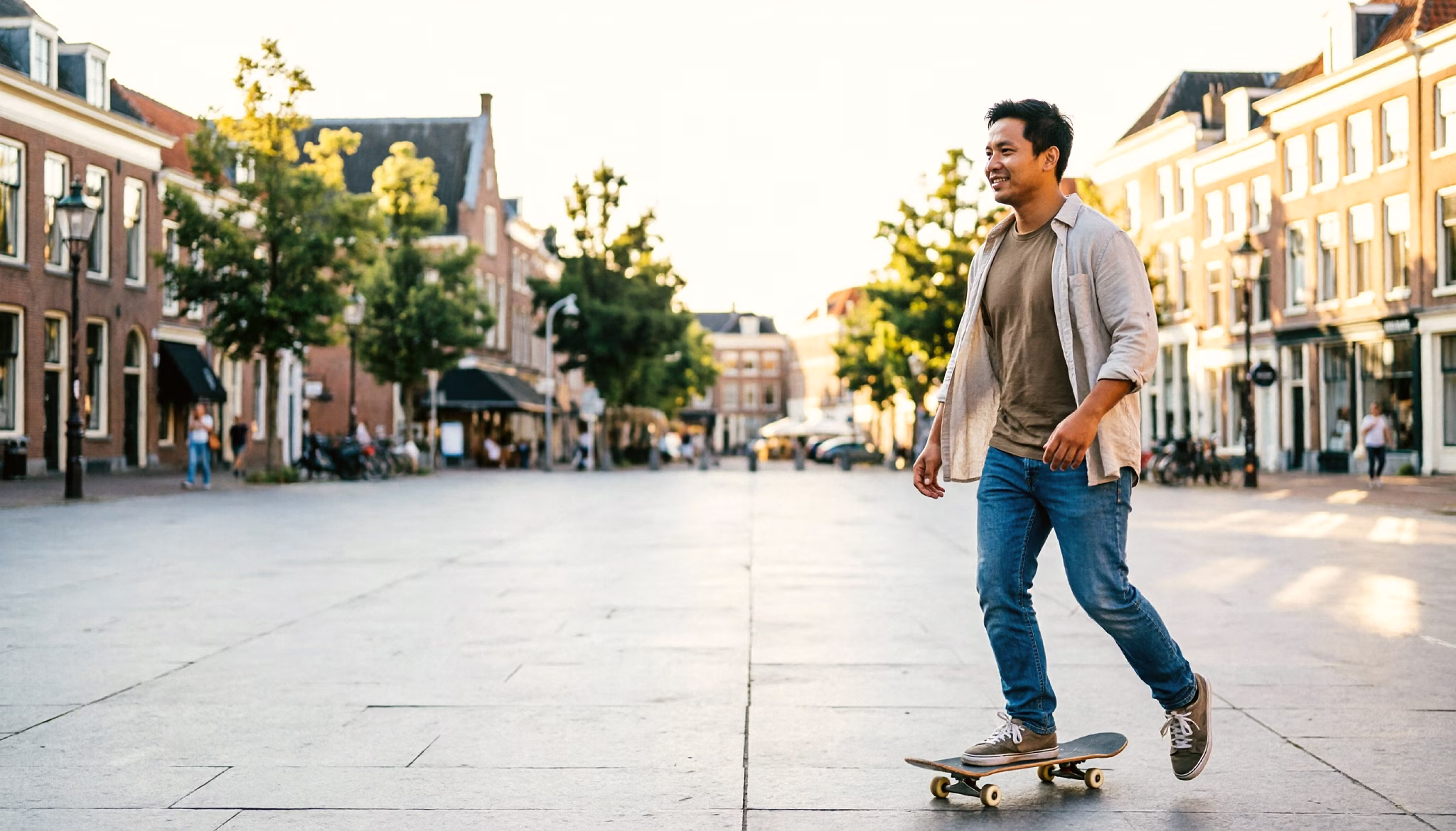 A young man skateboards at an easy pace across a sunny Dutch city square