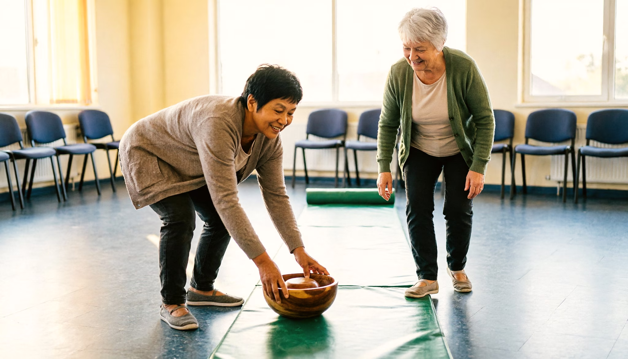 Two friends in their early sixties play a game of indoor bowls in a neighbourhood centre