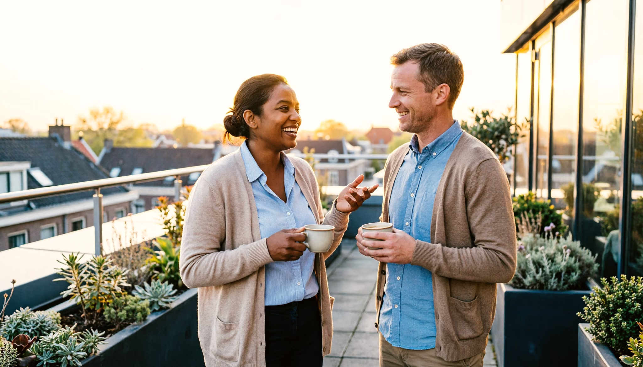 Two colleagues from different backgrounds chatting warmly over coffee in a modern office break area