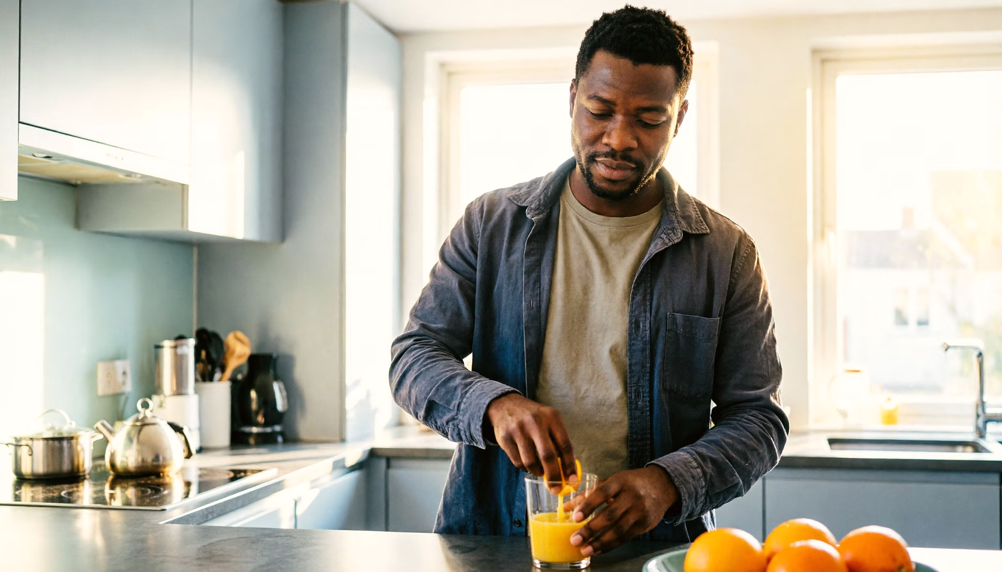 A man presses fresh orange juice at his kitchen counter on a calm morning