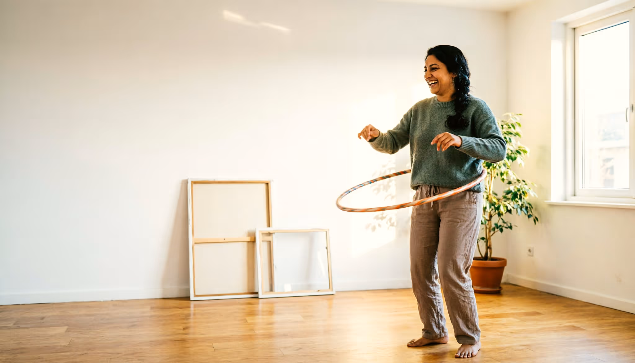 A young woman plays with a hula hoop in a sunlit Dutch living room